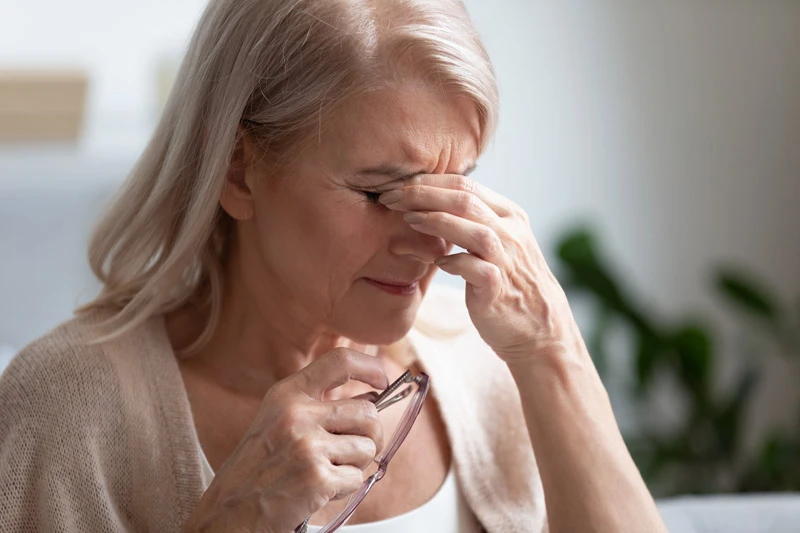 dry-eye-symptoms Older woman massaging the bridge of her nose and rubbing her dry eyes