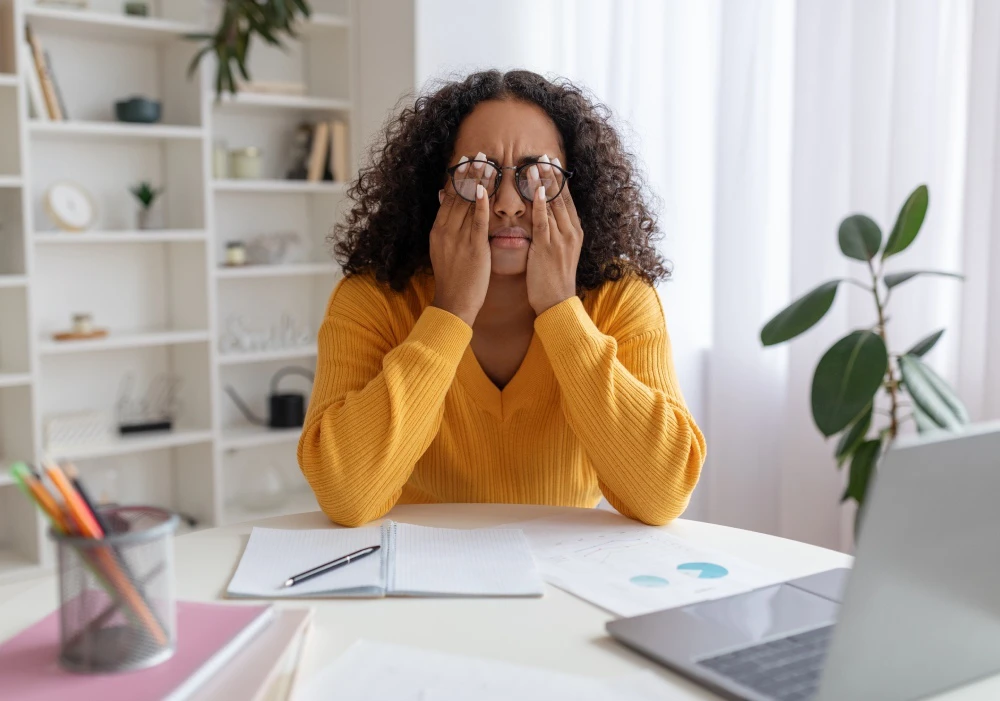 A woman holding her hands to her eyes and suffering from dry eye discomfort