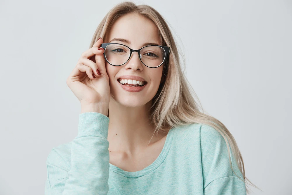Young woman wearing eyeglasses holding the arm of her glasses