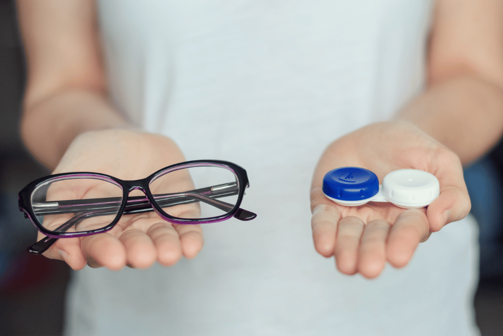 woman holding out a contact lens container and a pair of glasses